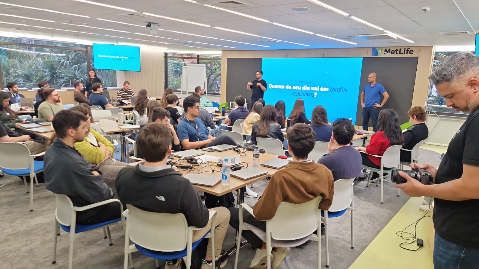 Dois facilitadores da Aimana passando instruções ao time da MetLife, com a pergunta do dia no telão